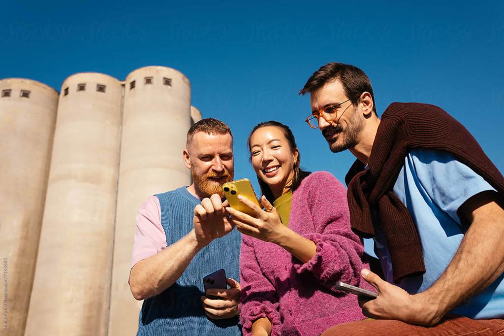 Three people having a discussion while looking at a phone